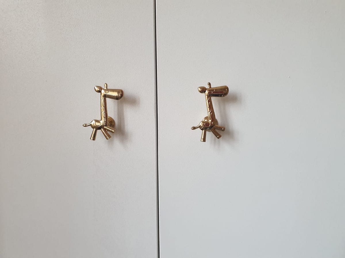 Detail of two brass wall-mounted taps against a plain painted wall