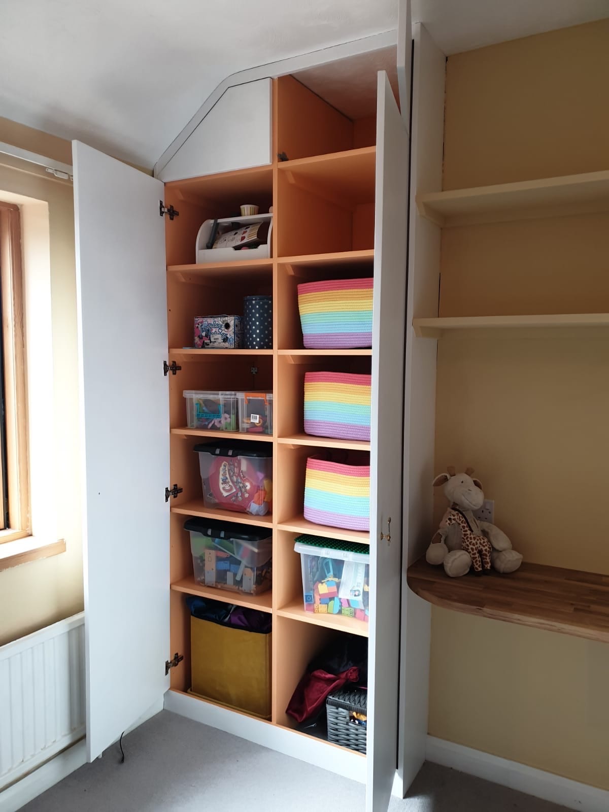 Alcove bookcase with cubby shelving and a built-in bench in a child's bedroom