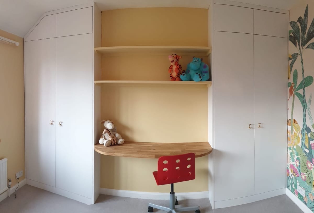 Children's bedroom with a fitted corner desk, shelving and built-in wardrobes
