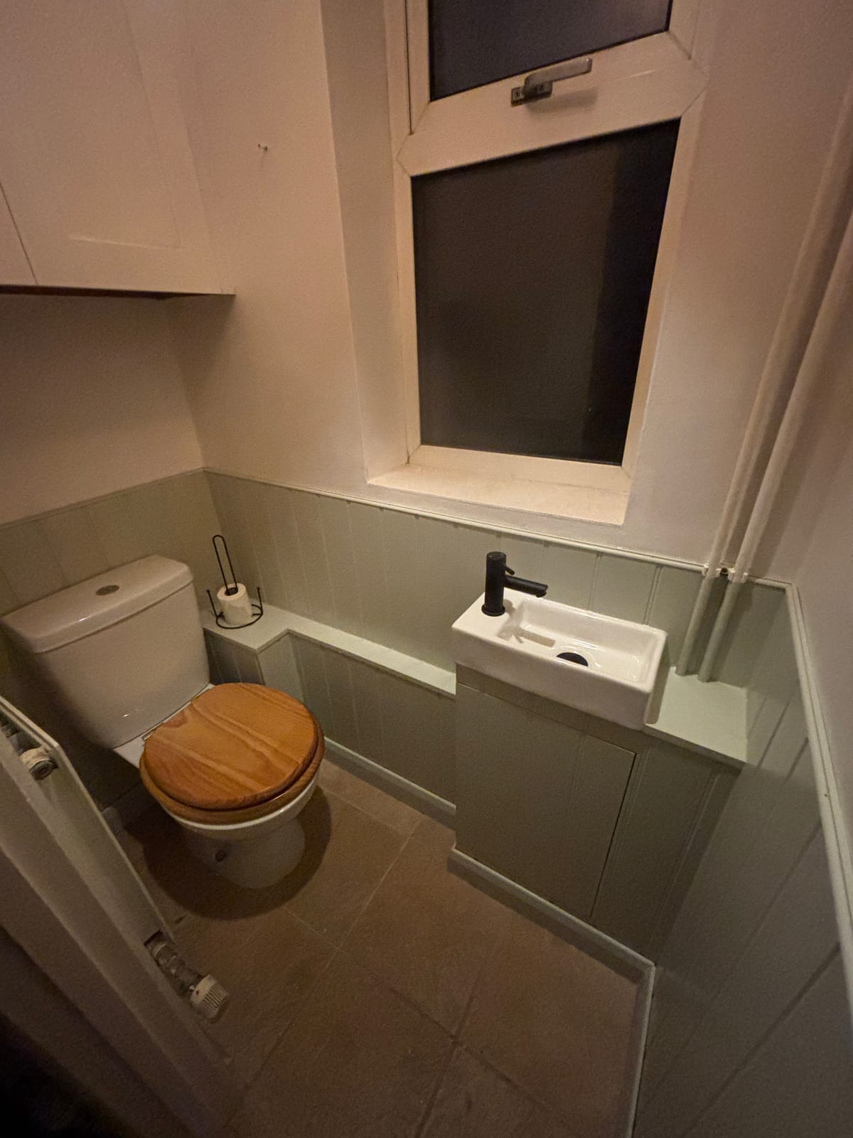 Compact bathroom with a concealed cistern, wooden toilet seat and tiled surround