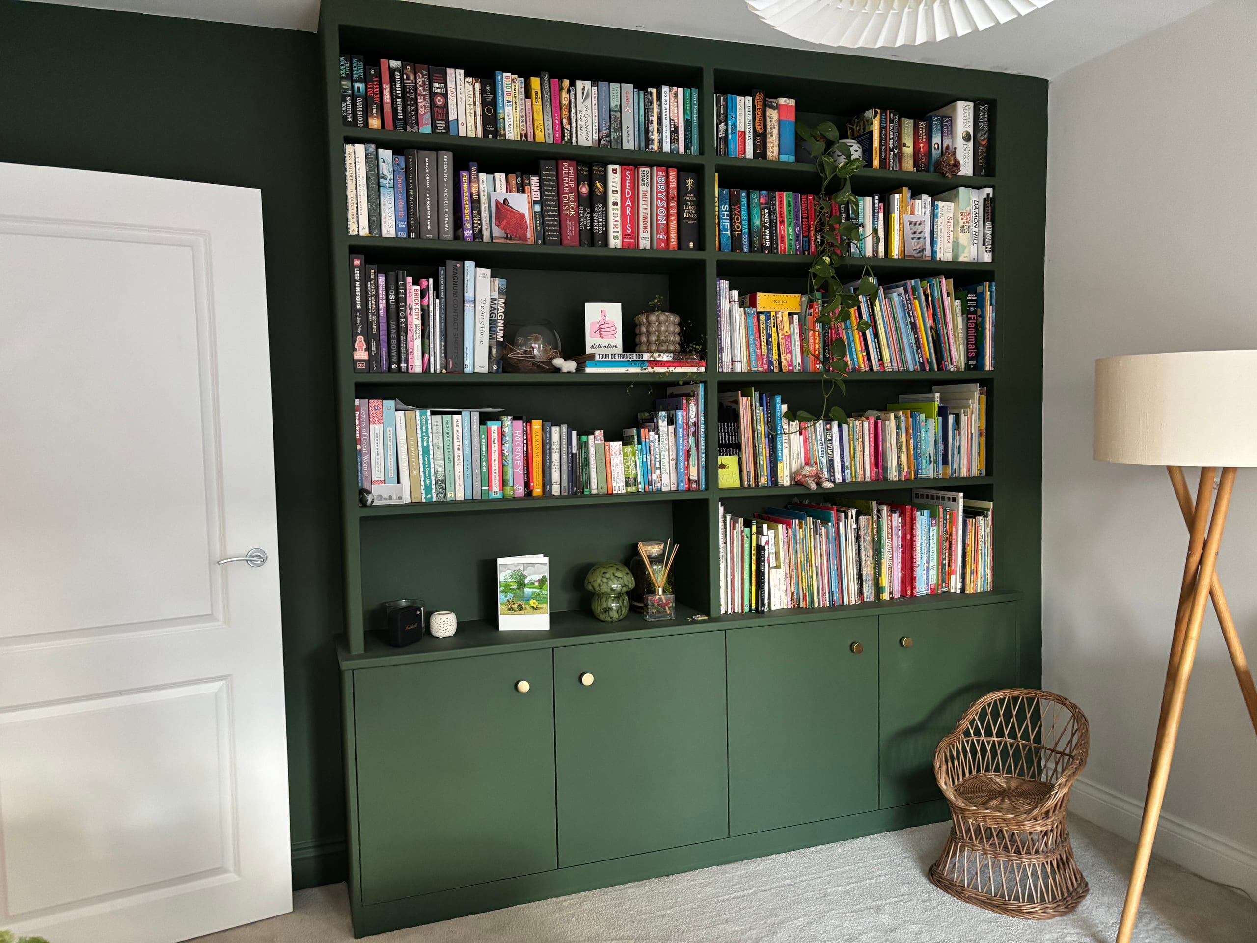 Floor-to-ceiling fitted library bookcase painted deep green, filled with books
