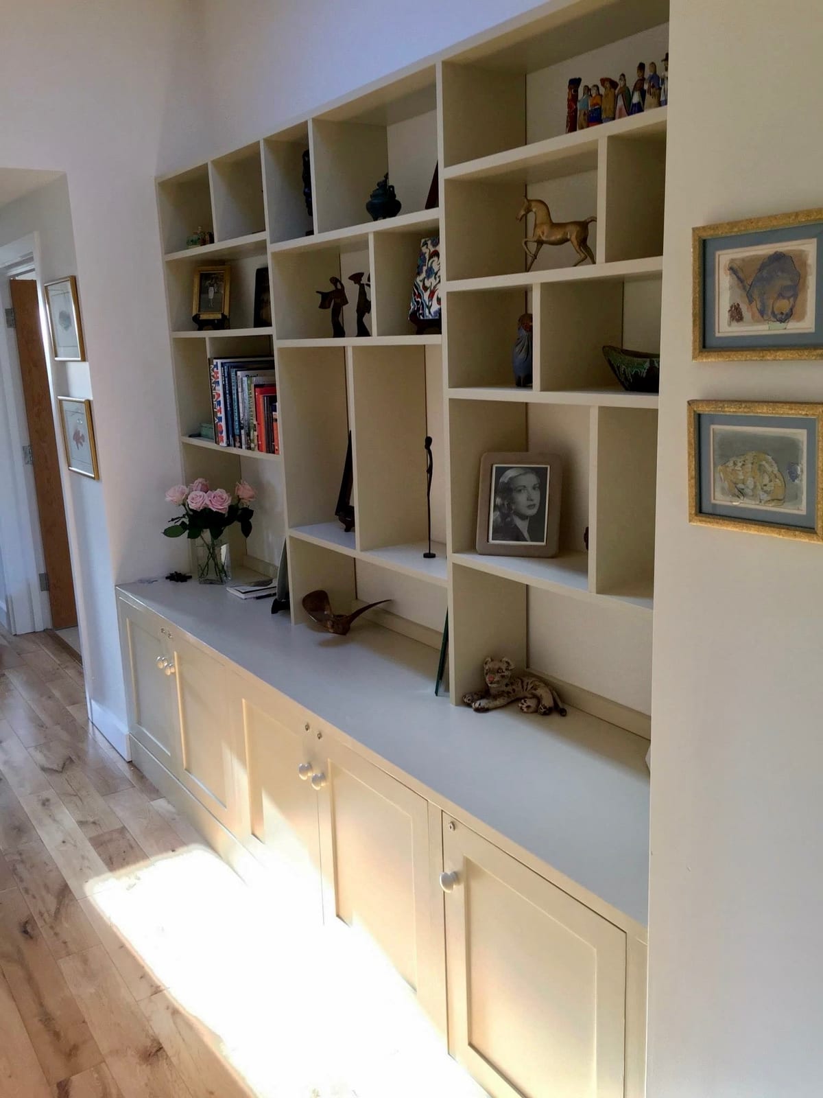 Fitted display shelving above a built-in bench with cupboards beneath