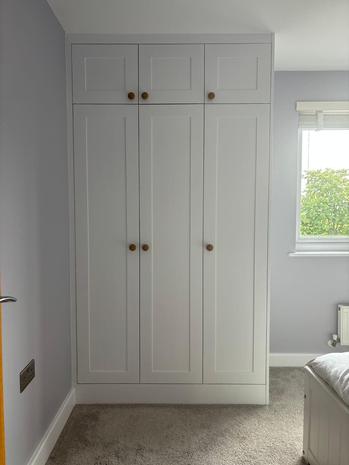 Built-in bedroom wardrobes painted white with brass knobs