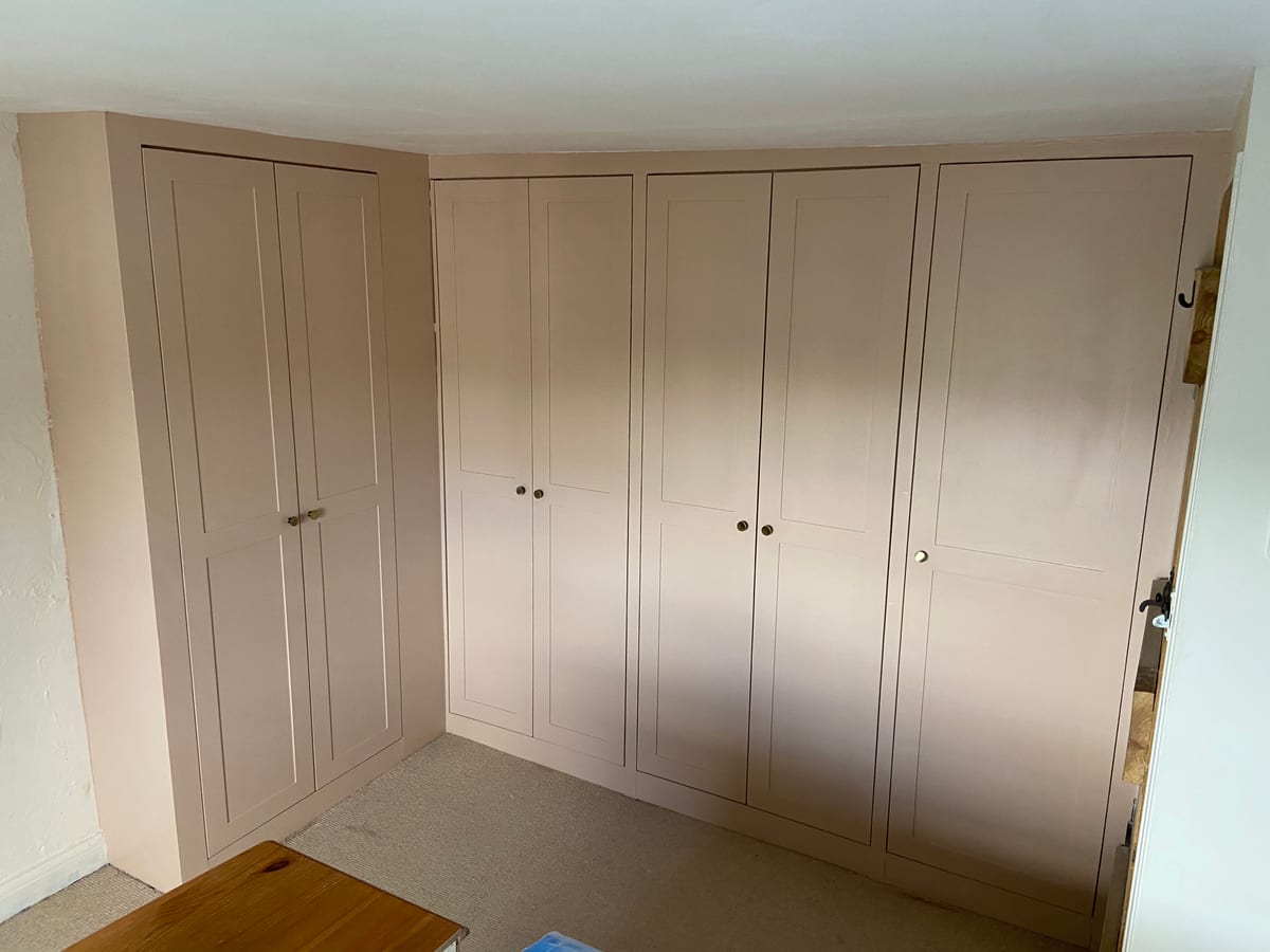 Run of floor-to-ceiling fitted wardrobes with shaker doors on a landing