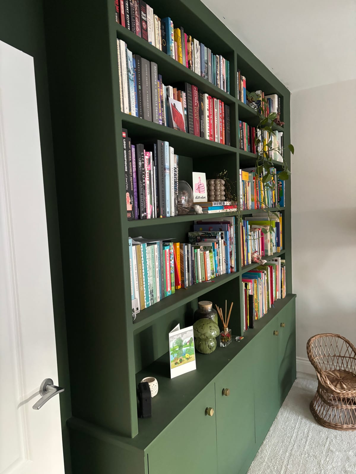 Fitted green library bookcase with cupboard bases, filled with books