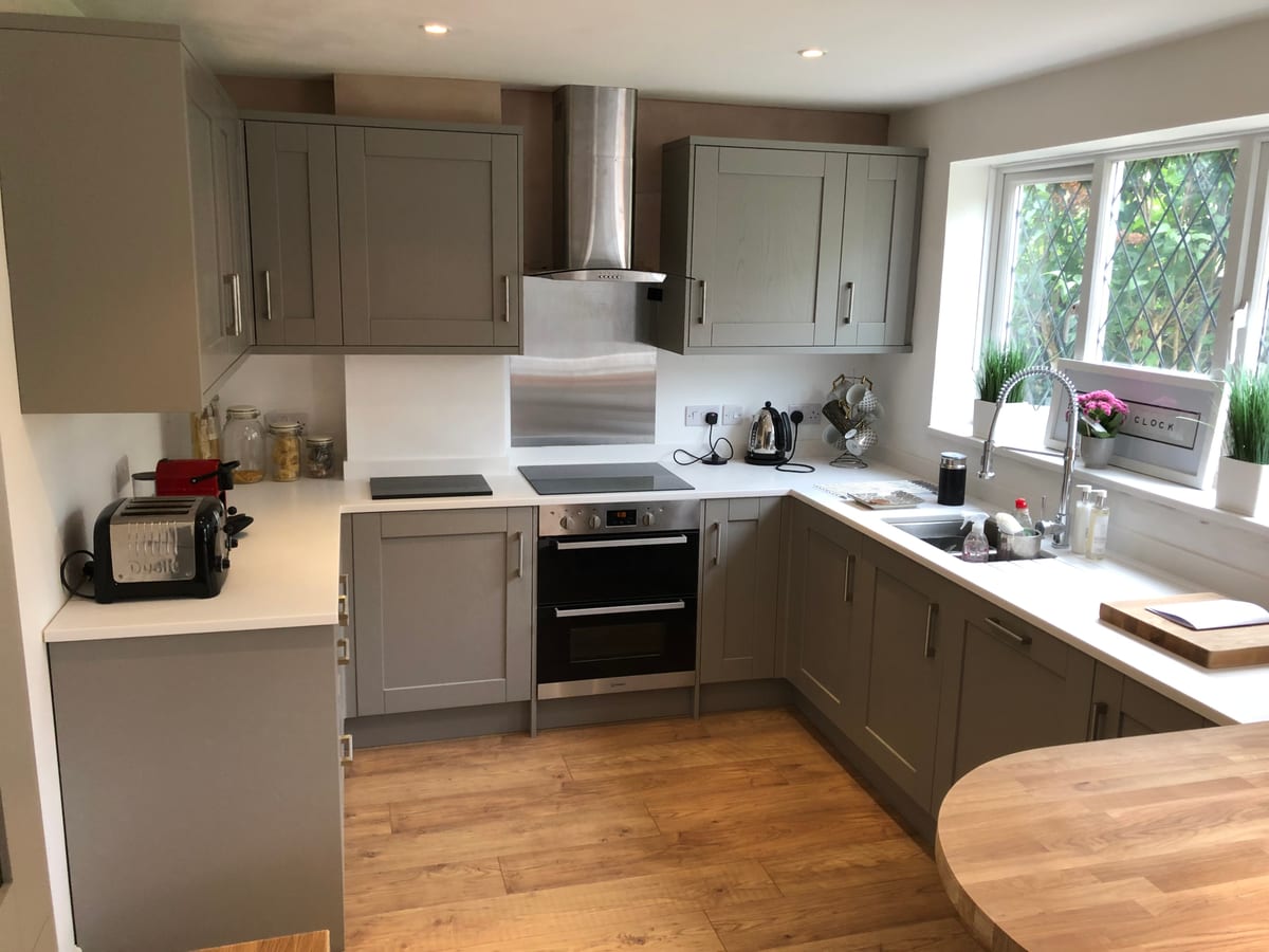 Grey shaker kitchen with a curved solid oak worktop and a garden window