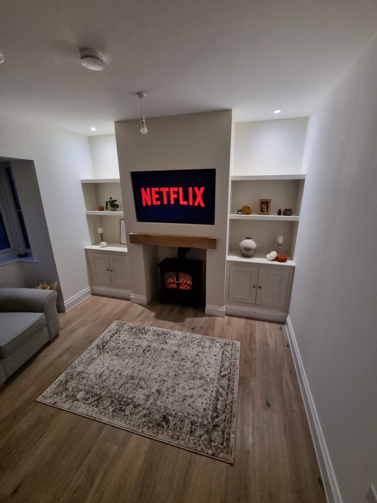 Living room with fitted alcove storage, an oak mantel and a wood-burning stove