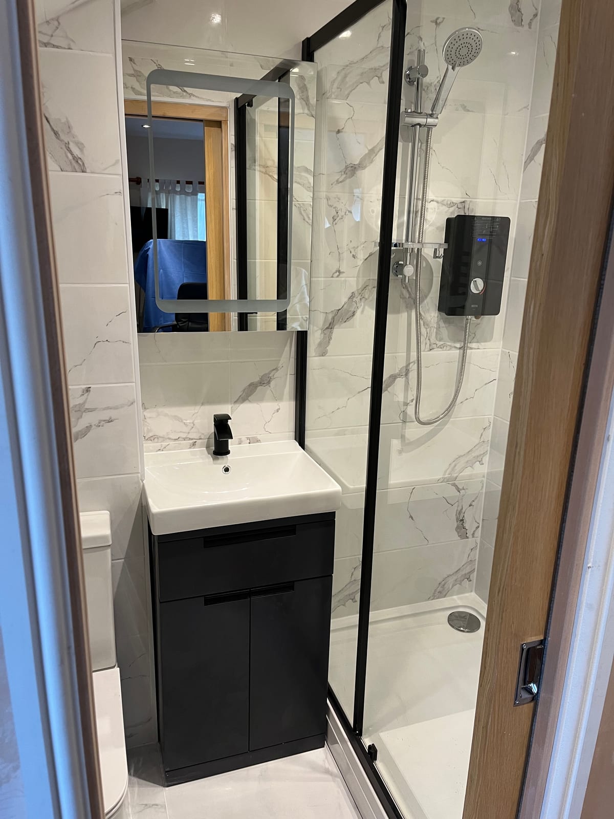 Shower enclosure with marble-effect tiling, black fittings and a vanity basin