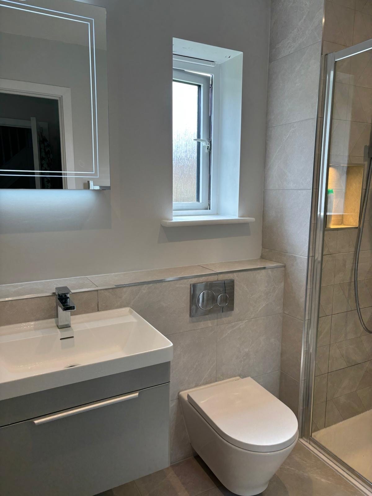 Modern shower room with a wall-hung vanity unit, back-lit mirror and wall-hung WC