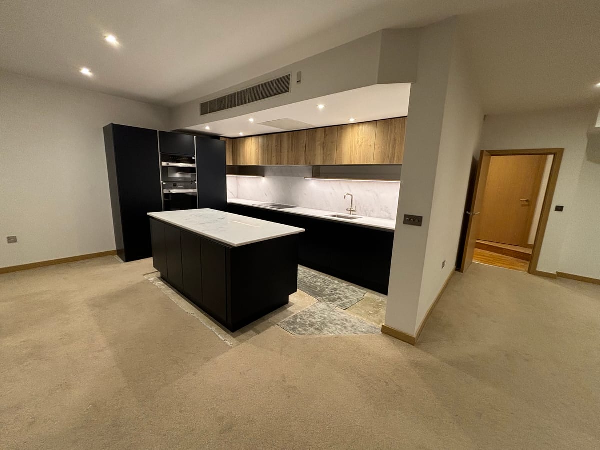 Open-plan black kitchen with a central island and recessed ceiling lighting