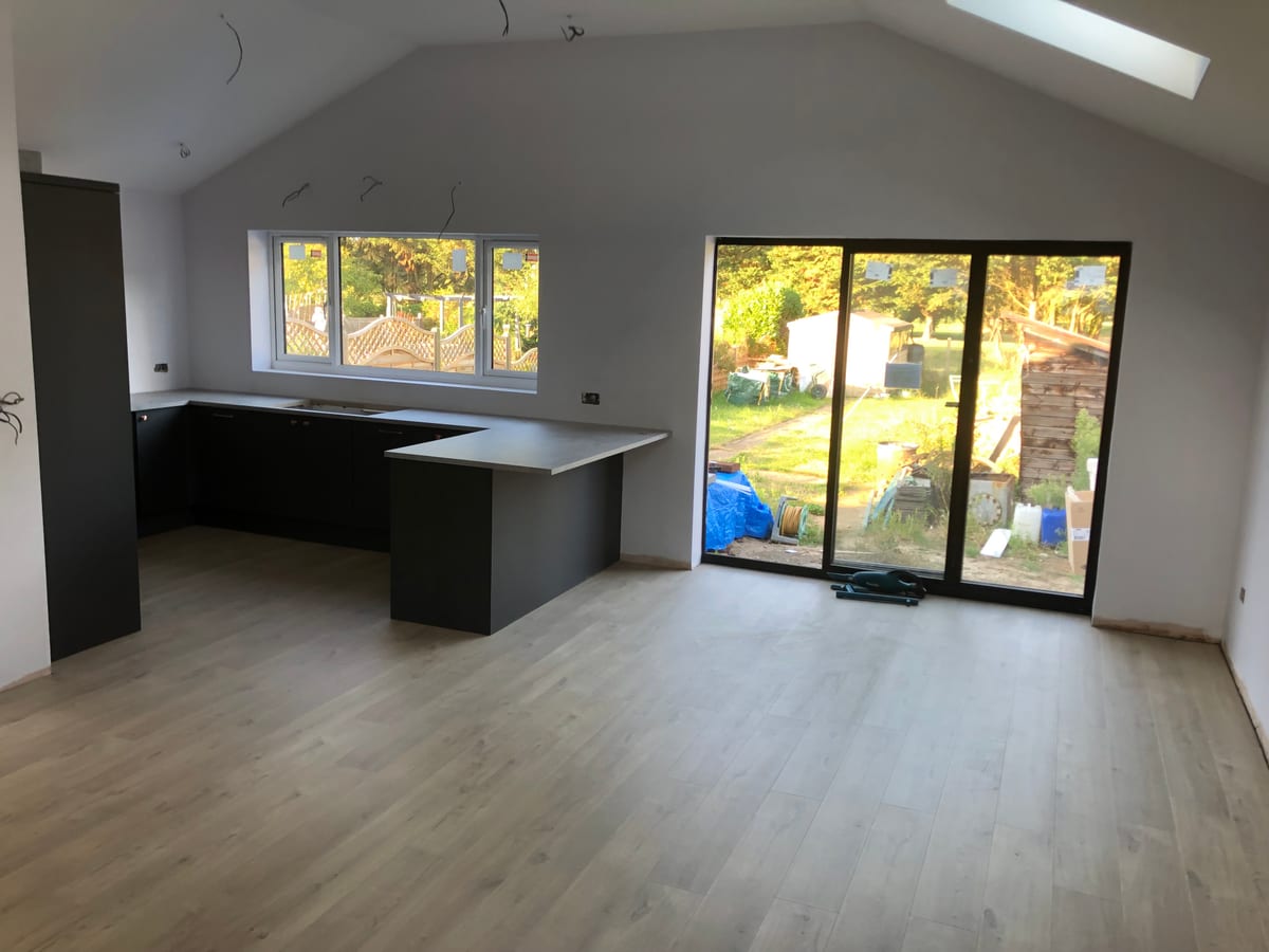 Open-plan kitchen with a dark peninsula and full-height garden doors