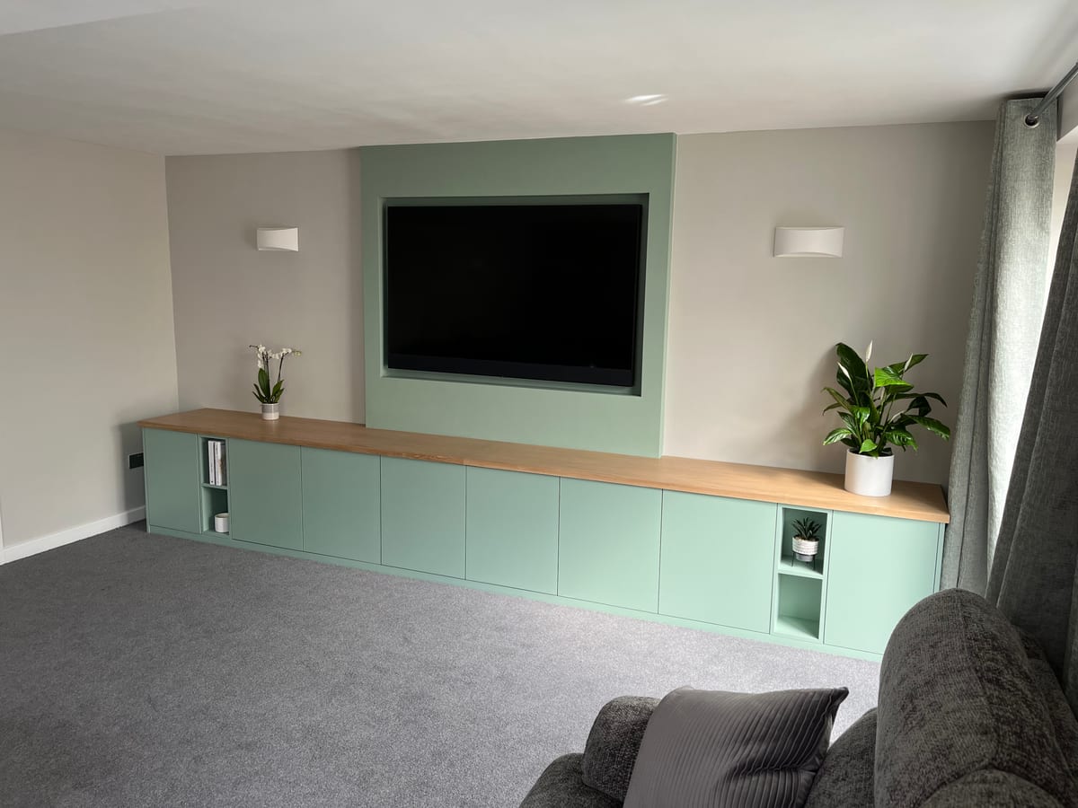Sage green fitted sideboard with an oak top and open display niches