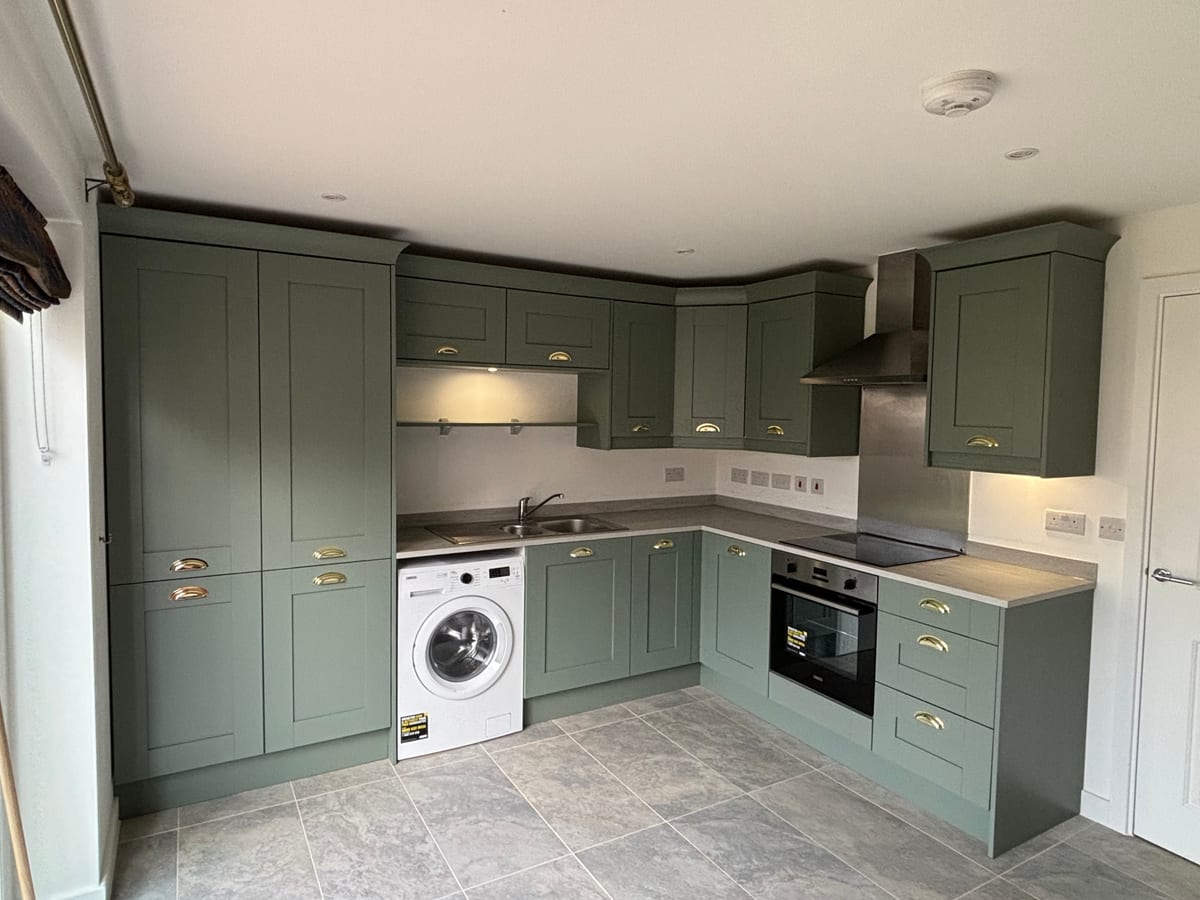Sage green shaker kitchen with integrated washing machine and tiled flooring