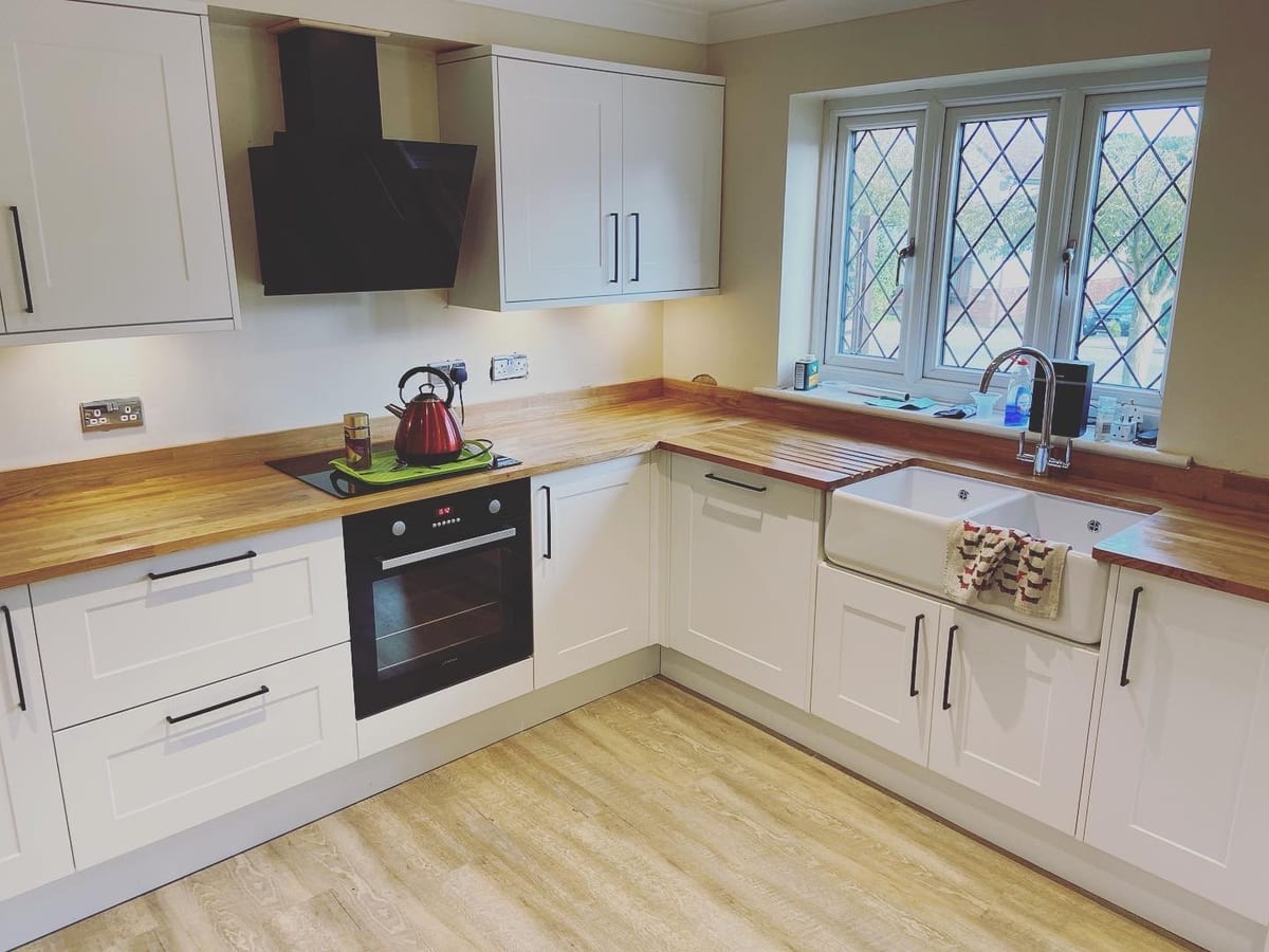 Cream shaker kitchen with solid oak worktops and a Belfast sink beneath a leaded window