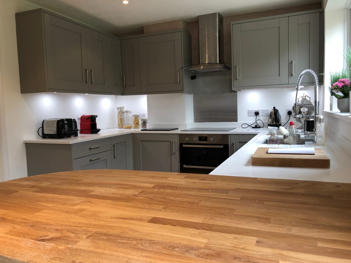 Detail of a shaped solid oak worktop meeting a white quartz surface