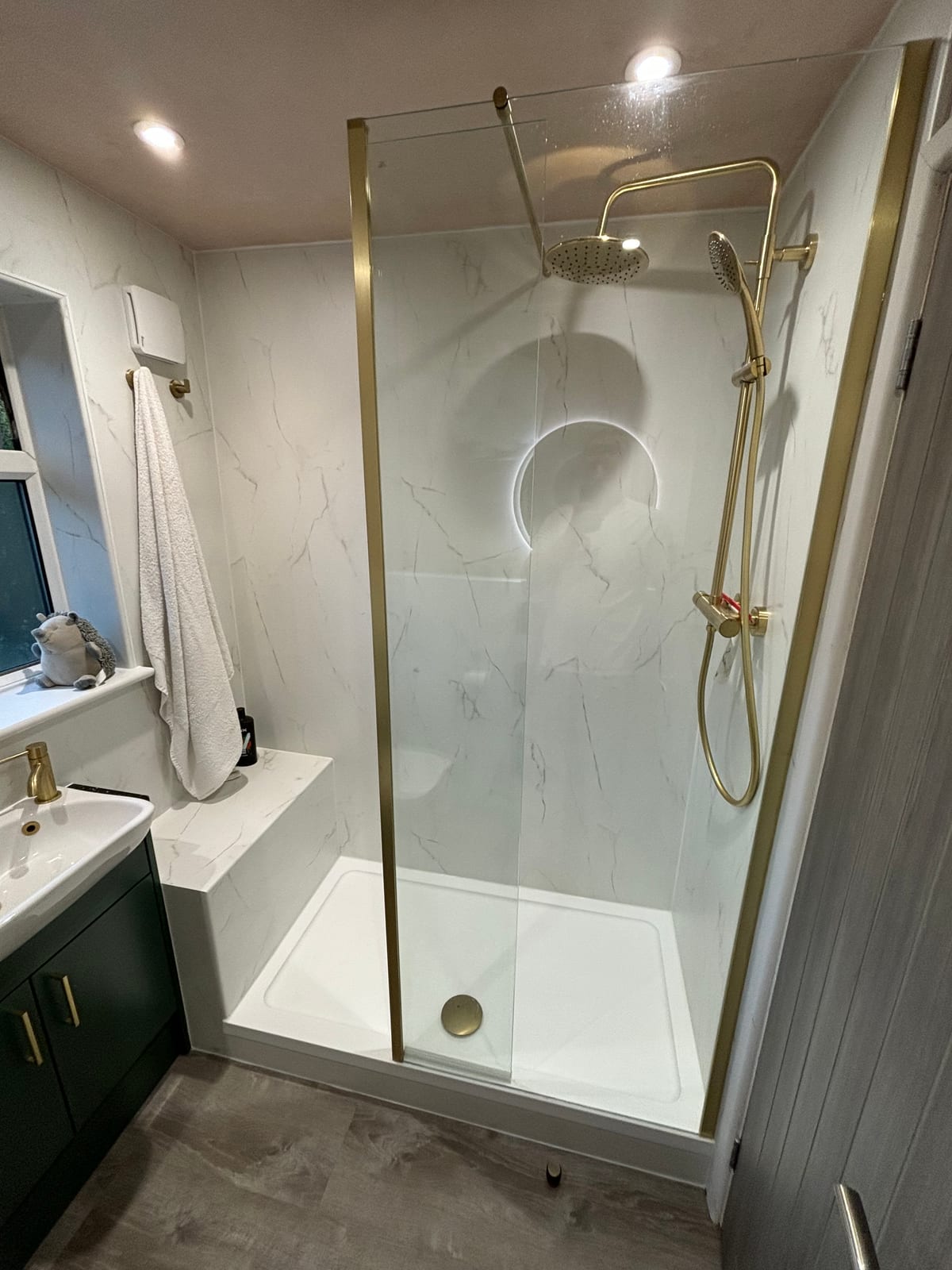 Walk-in shower enclosure with brass fittings and marble-effect wall tiles