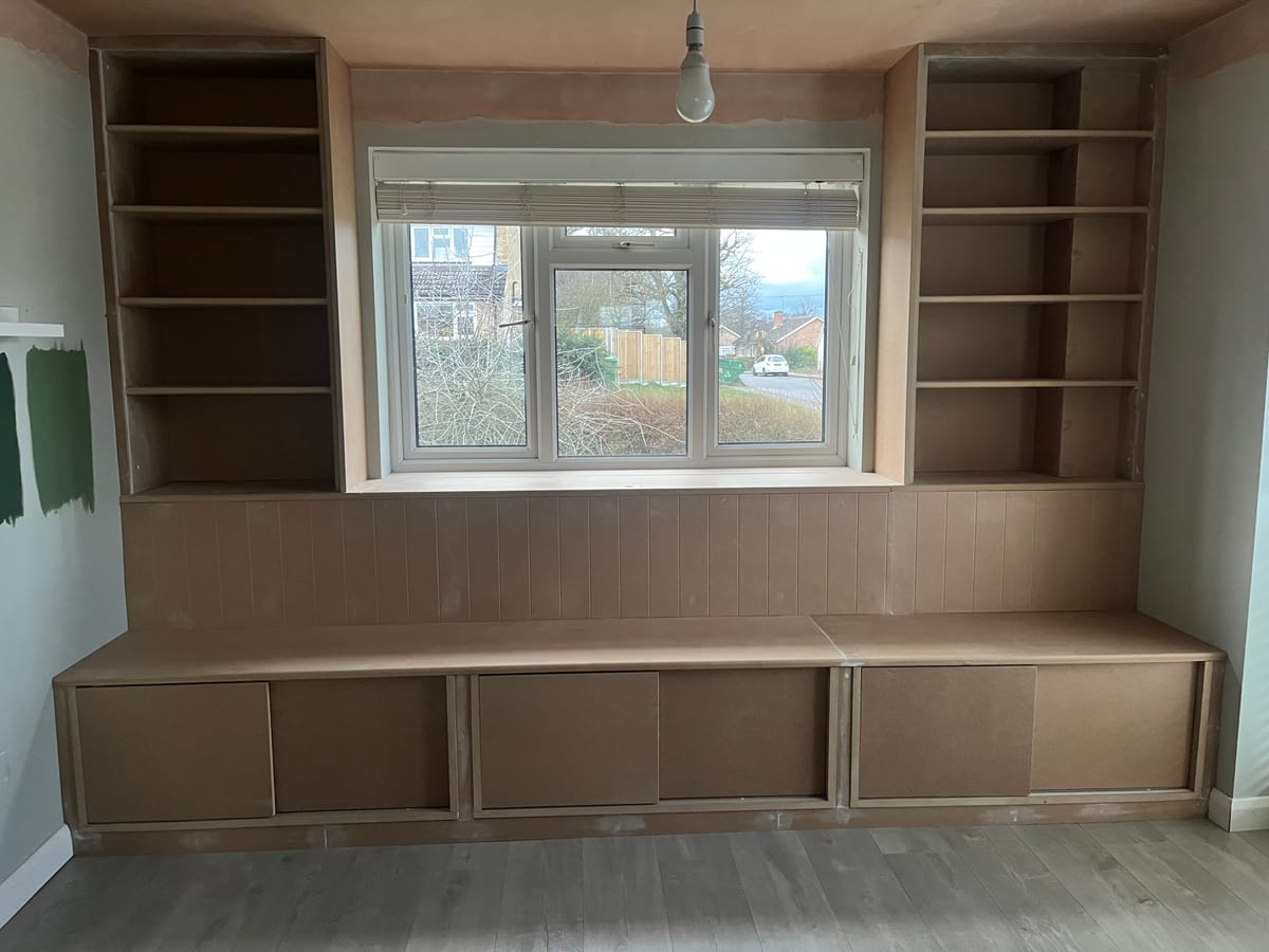 Fitted window seat with drawer storage and shelving either side of a window
